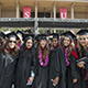 CSUN graduates standing together on commencement day with Oviatt Library in the background.