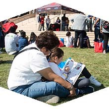 A mother and daughter sit on the lawn in front of the Oviatt Library to read a book at last year's Feria de Education.