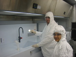 Mike Dickson and Yogeshwari Patel are cleaning a Silicon wafer in the class 100 chemical hoods in the cleanroom