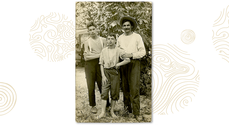 A man and two boys posing on a black and white family photo.