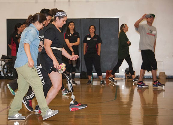 PT students lead a person with a prosthetic leg in a walk exercise
