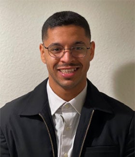 Male Student, Ammar Al Harthy, wearing a black jacket and white button-up shirt