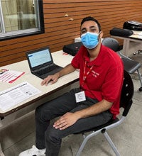 CSUN Vita Student volunteer wear a mask and red polo shirt