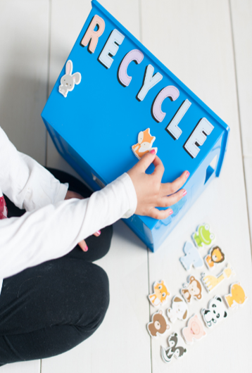 A recycling bin being decorated by a child