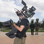 a student stands atop the oviatt library with filming equipment