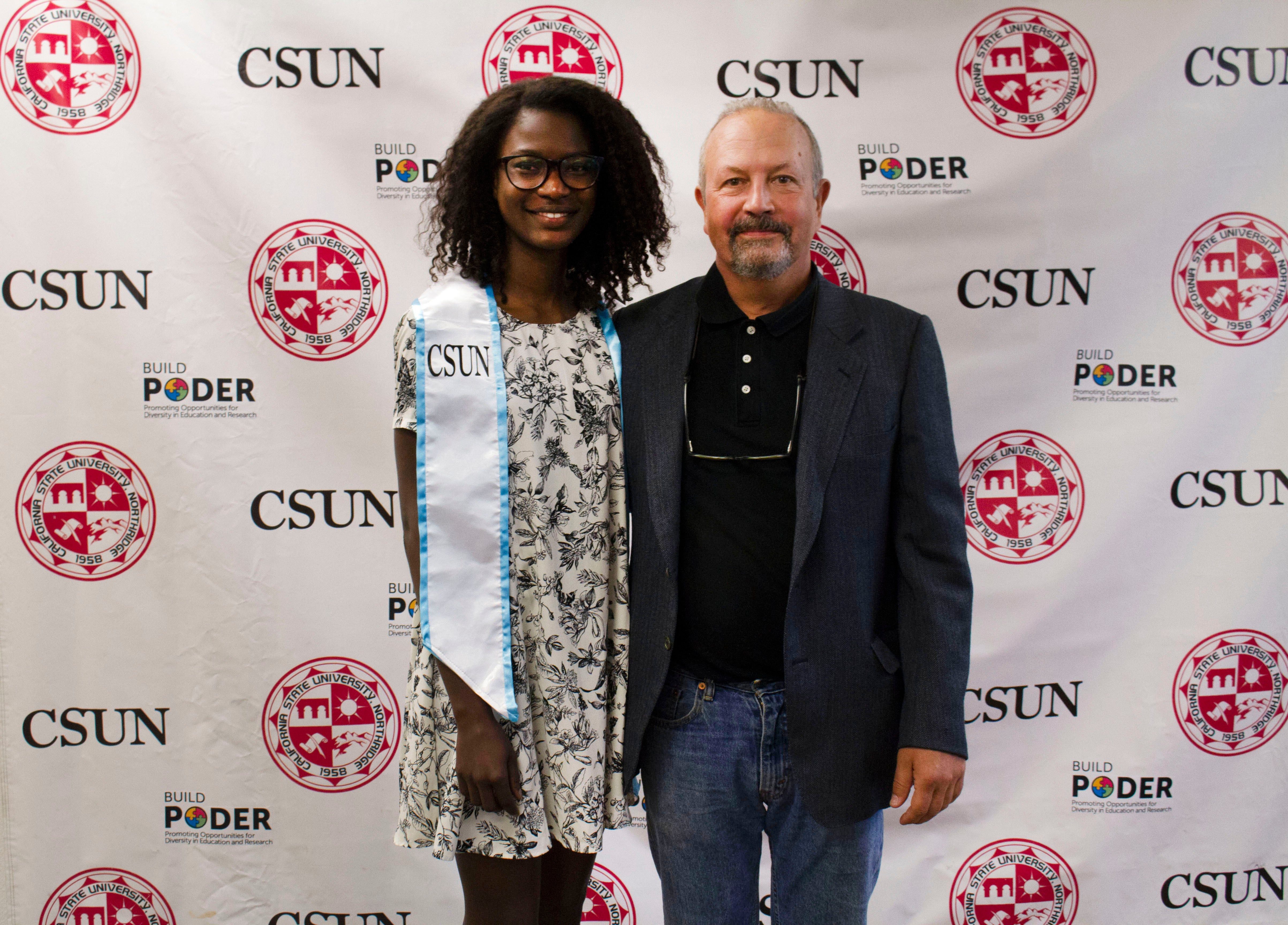 Umu smiles at camera while standing next to mentor Dr. David Bermudes