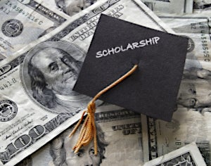 Graduation cap on top of a pile of money.