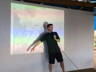 Luke Drake standing in front of a projected map, lecturing in Port Vila, Vanuatu, 2017