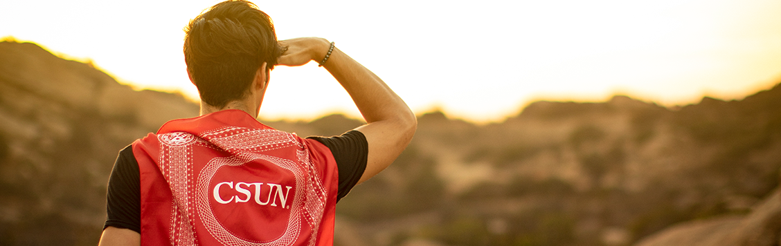 Student looks on ahead as the CSUN flag rests on his back