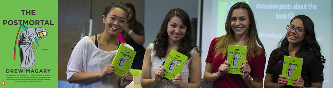 Four smiling students hold copies of THE POSTMORTAL