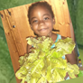 Young girl holding a bunch of lettuce and other produce.