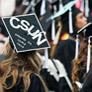 commencement scene with graduate wearing mortarboard that has &quot;dreams do come true&quot; written on it.