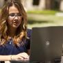 A photo showing a female CSUN student using her laptop outdoors.